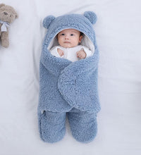 Baby in blue quilted sleeping bag wrapper with bear ears, soft cotton blend, perfect for cozy naps.