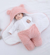Cute baby wrapped in pink quilted sleeping bag with bear ears, promoting warmth and comfort for infants.