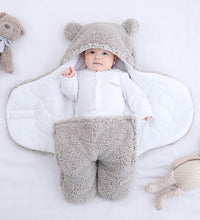 Baby in a cozy bear-themed quilted sleeping bag on a soft surface, surrounded by plush toys.