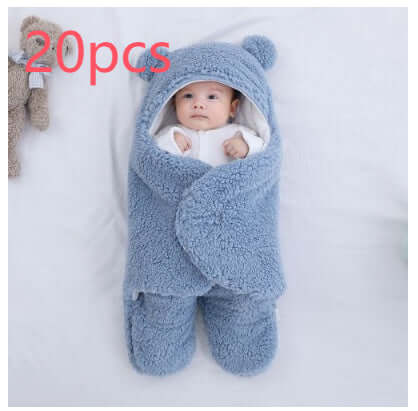 Baby wrapped in a cozy cream quilted sleeping bag with bear ears, beside a fluffy teddy bear.